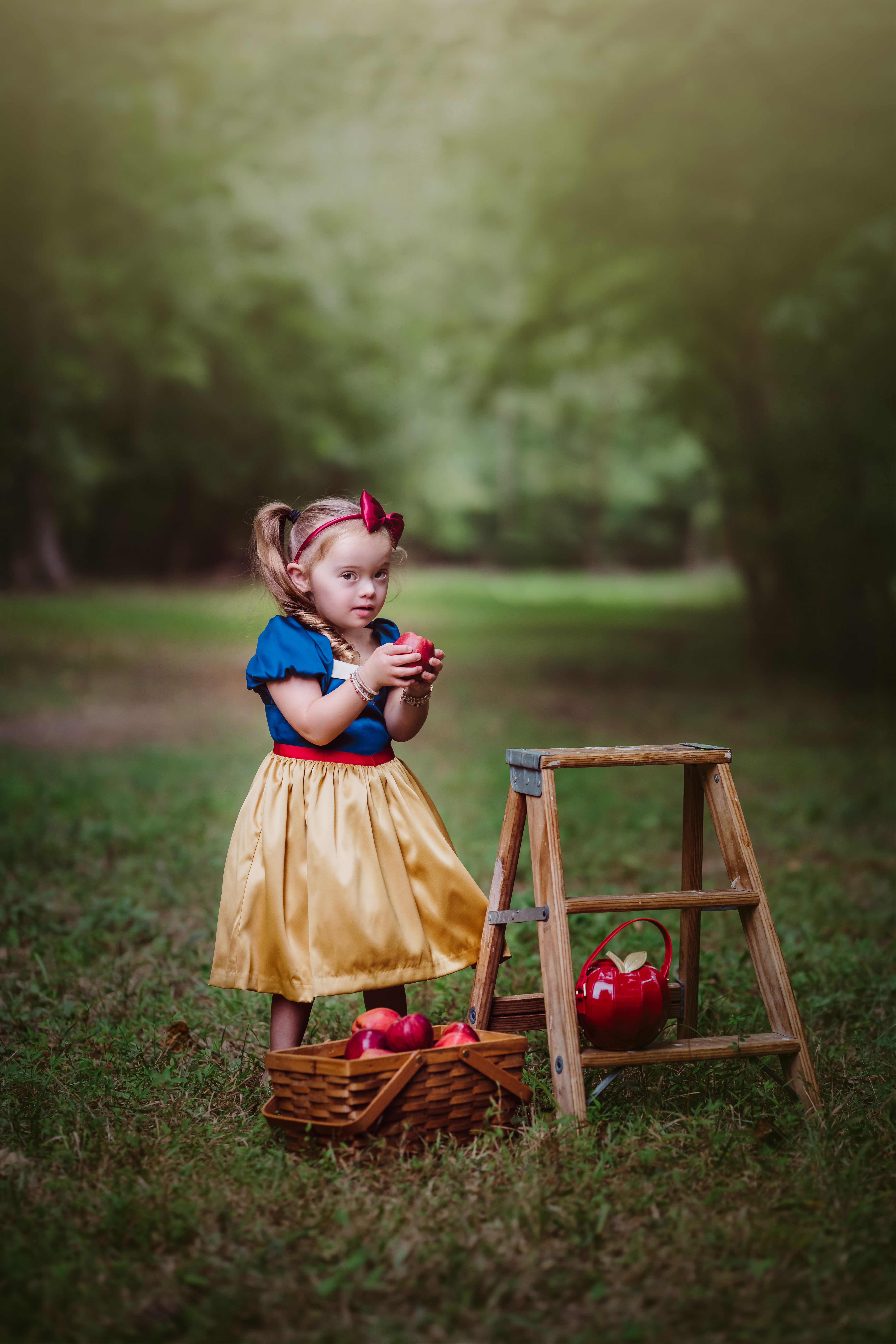 a little girl with down syndrome plays dress up as snow white with apples