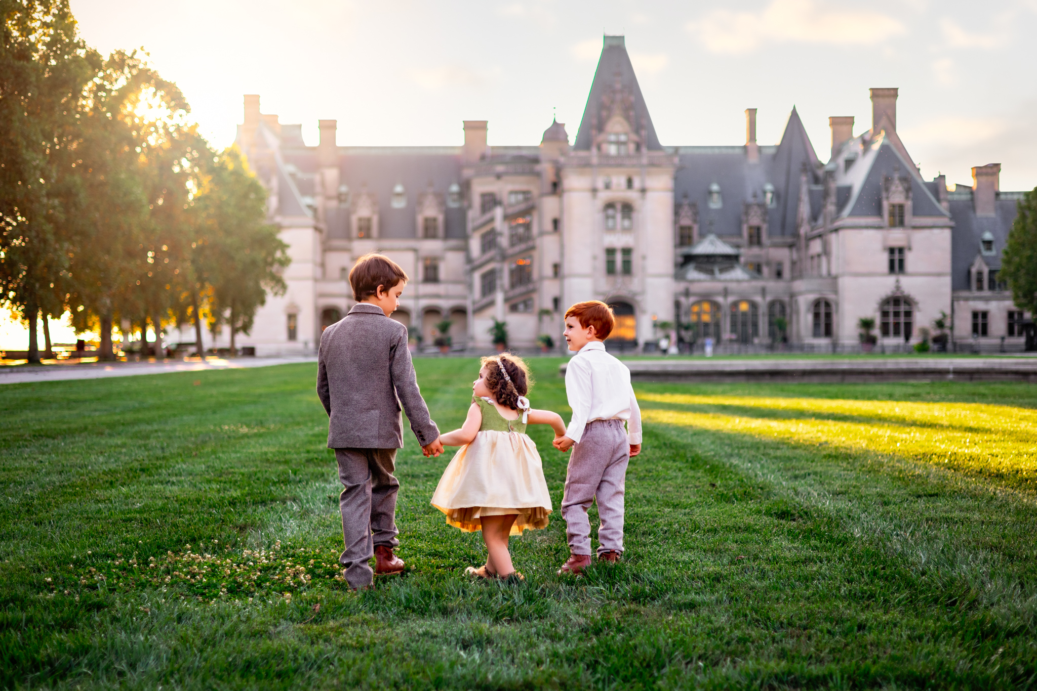 three young children playing and holding hands in front of the Biltmore Estates