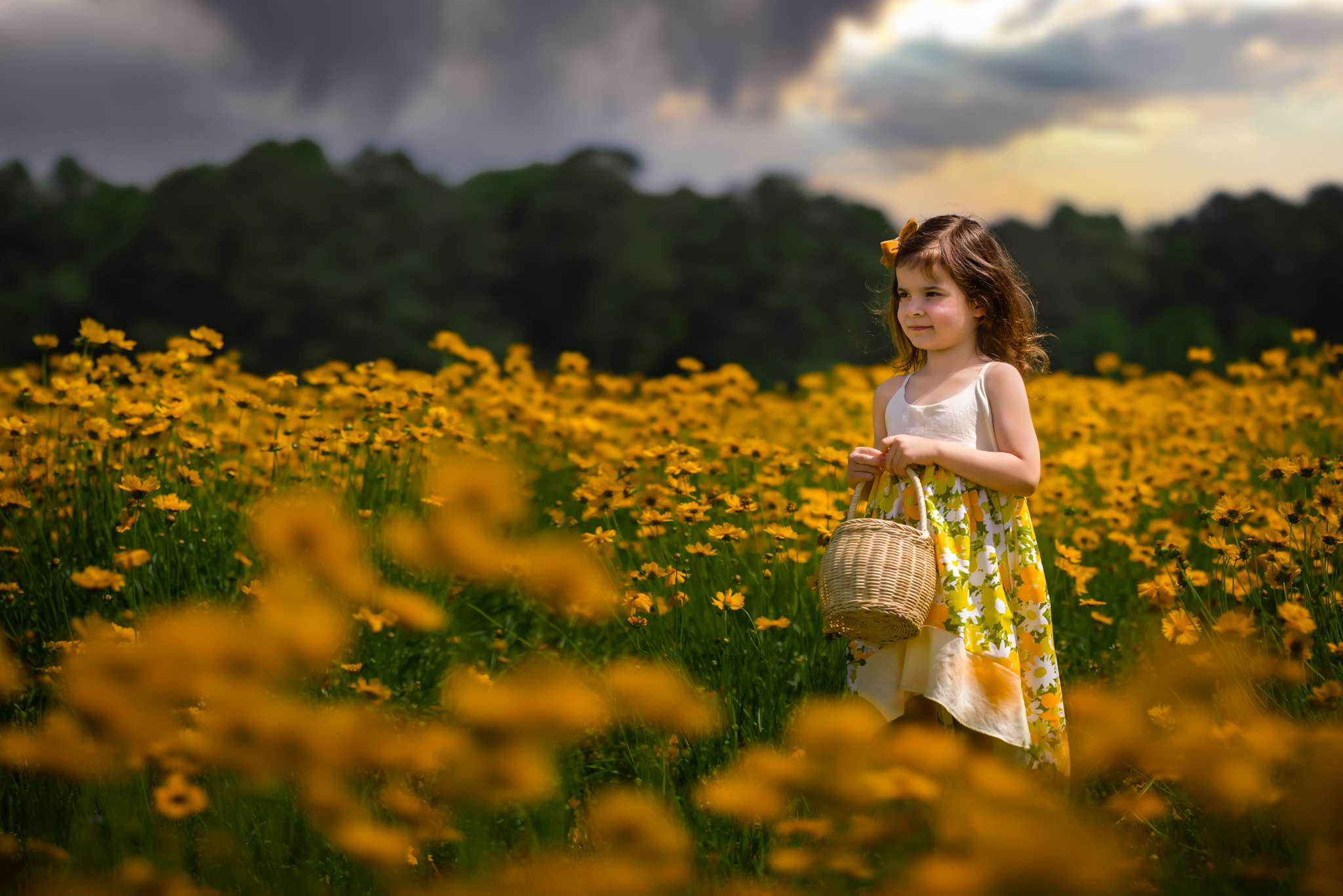 young girl standing in a field of yellow flowers holding a basket