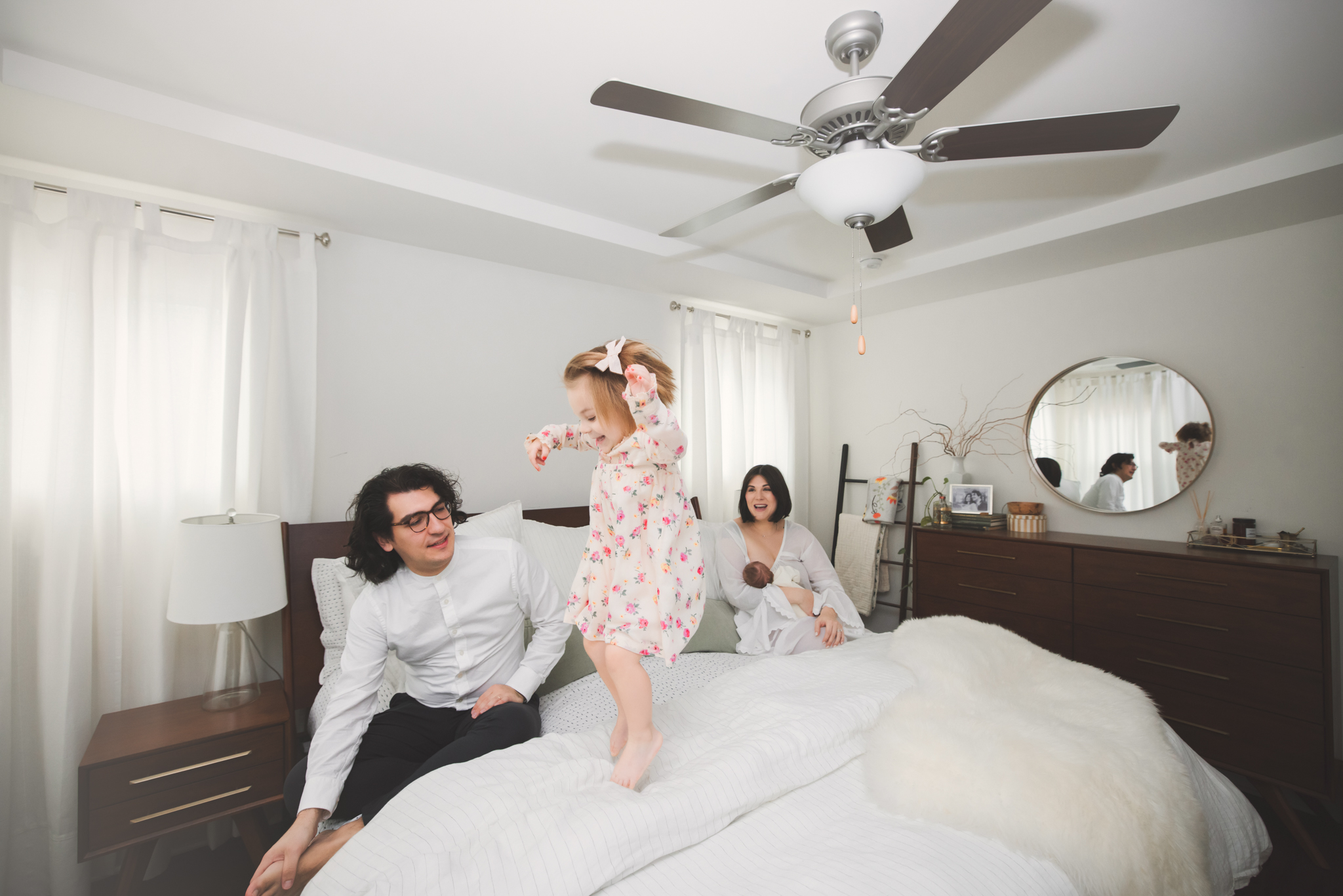 Family at home with little girl jumping on the bed