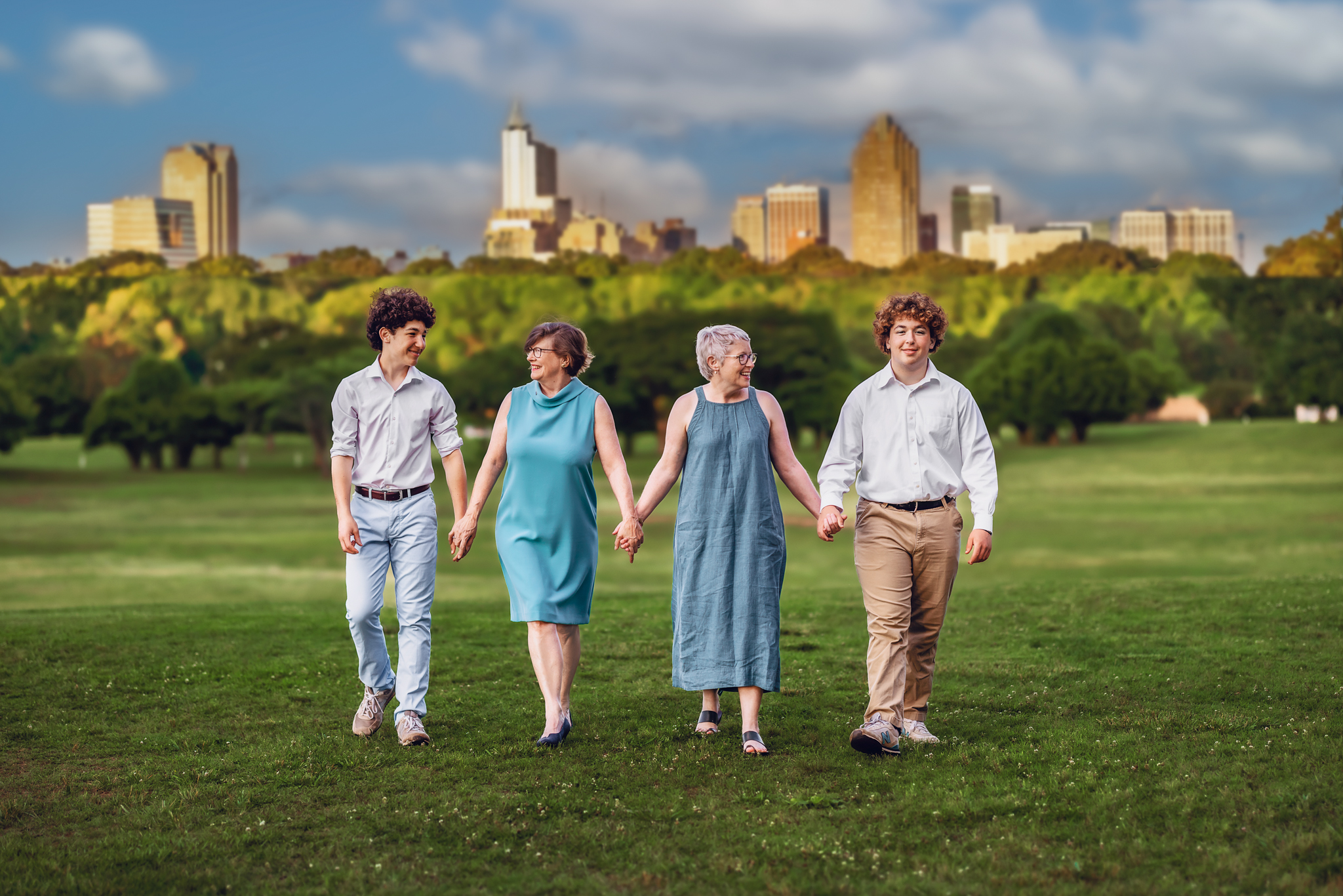 Family walking holding hands with the Raleigh, NC skyline in the background