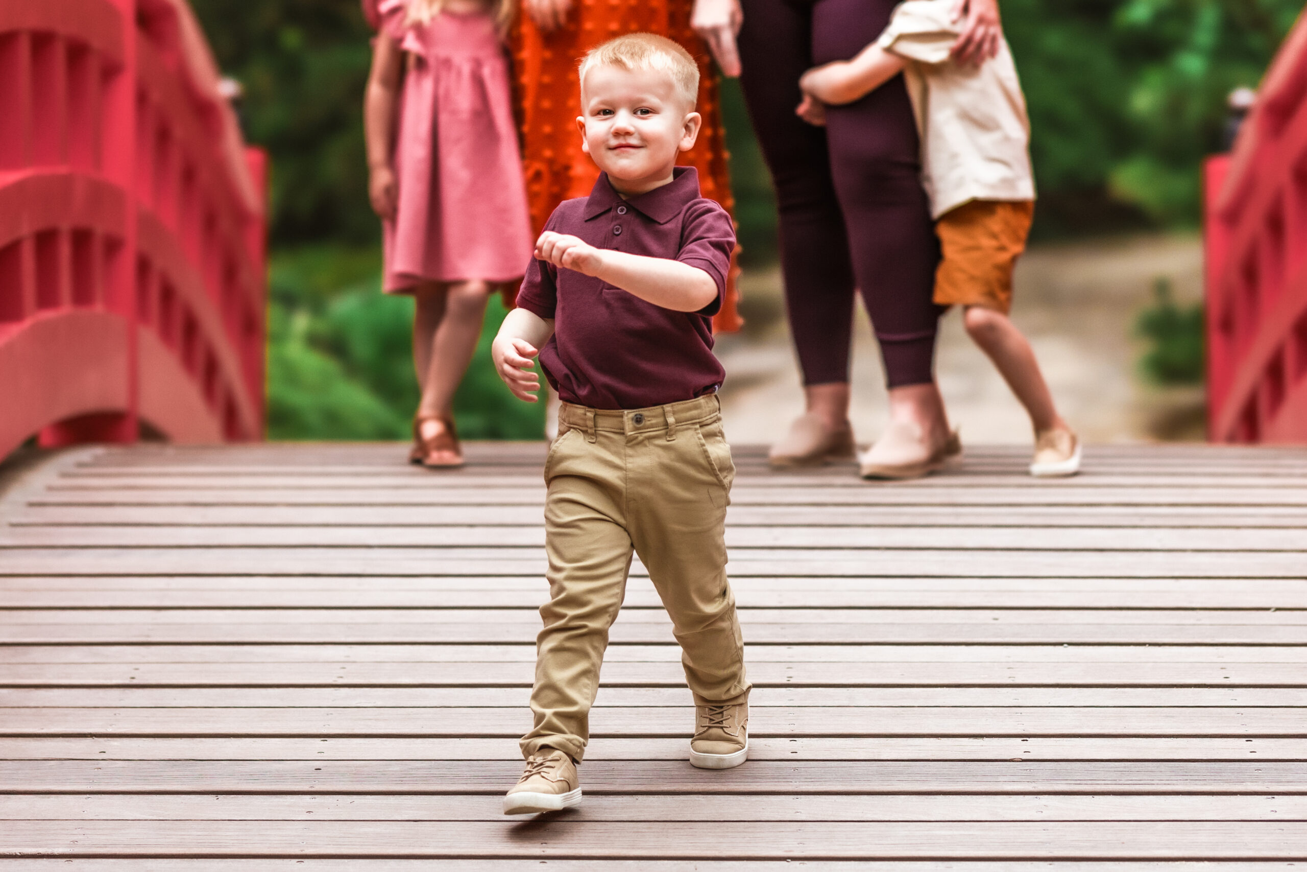 little boy laughing and running from his family